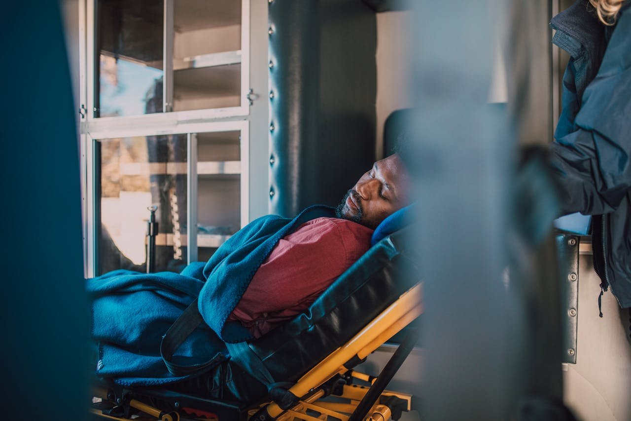 digital A serene depiction of an African American man resting on a stretcher in a medical vehicle, wrapped in a blue blanket.