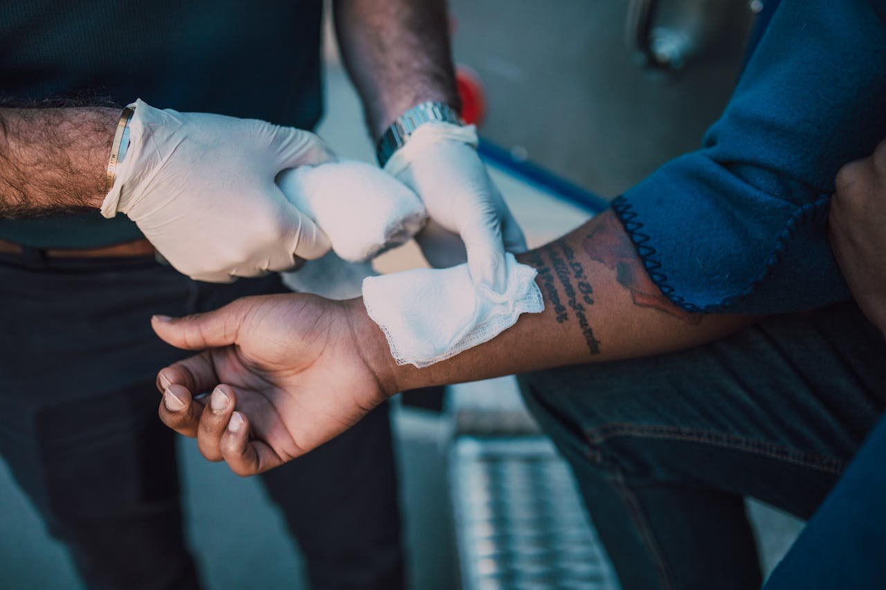 Services-01 A healthcare professional in gloves applying a bandage to an injured arm, focusing on first aid care.