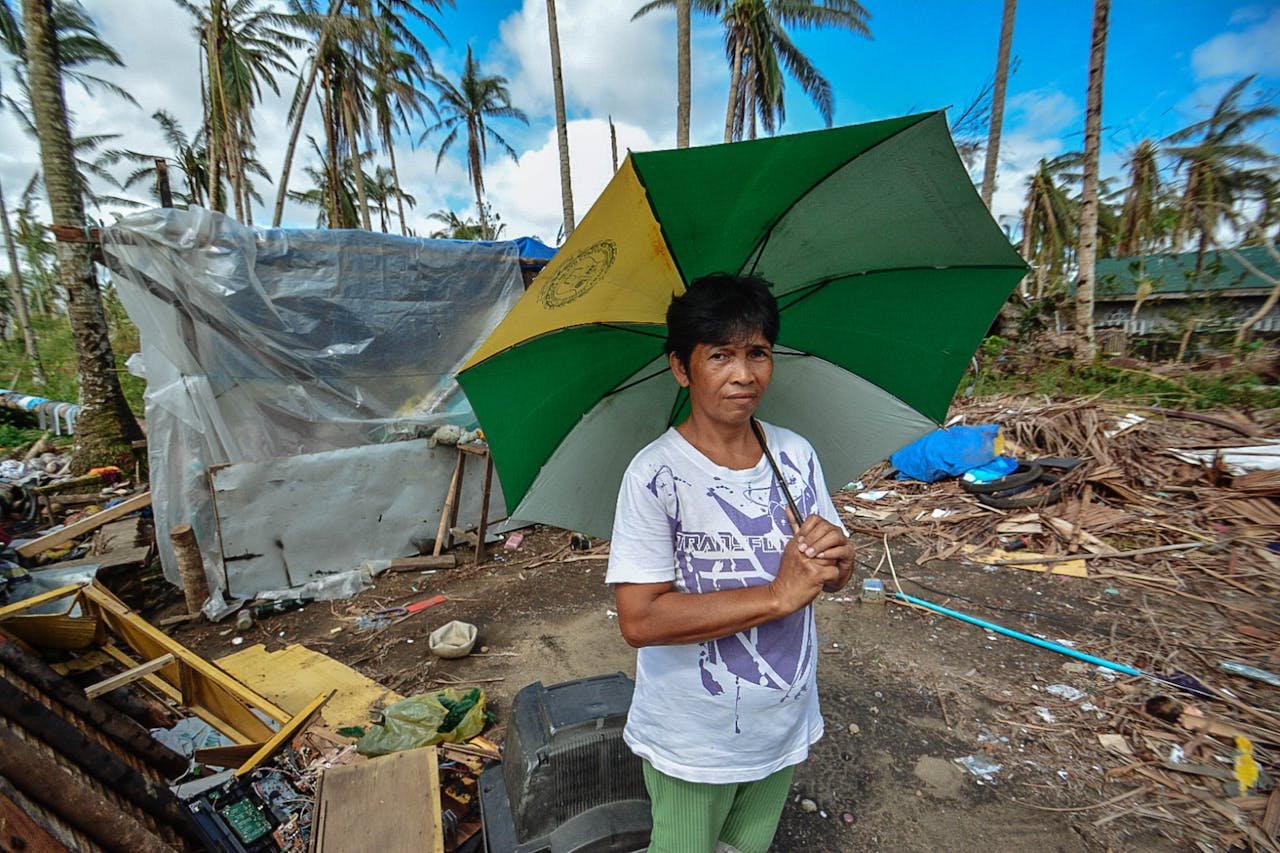 why-choose-us Asian woman holding an umbrella amidst storm aftermath with scattered debris.